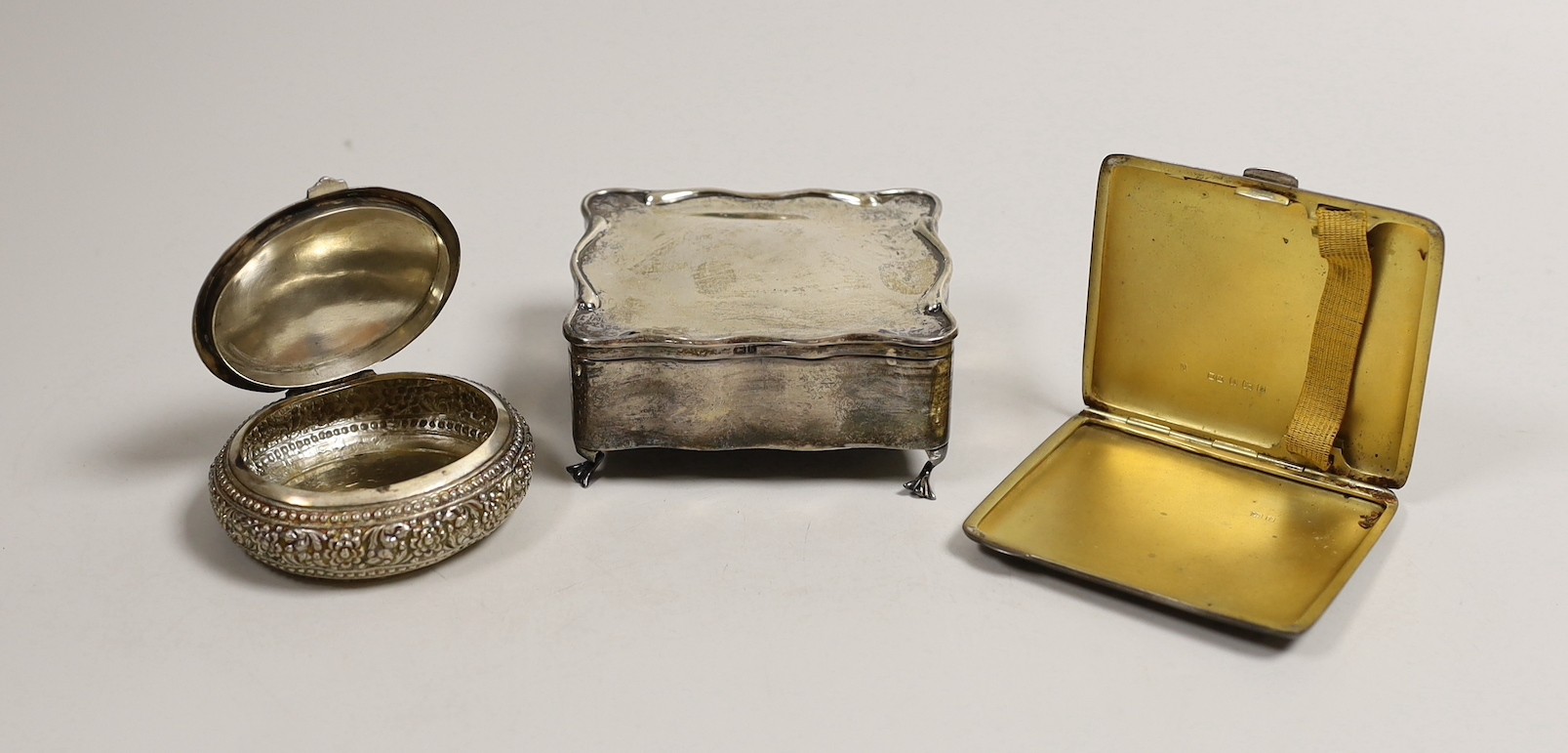 An Edwardian silver trinket box, Birmingham, 1907, 90mm, a silver cigarette case and a Persian? white metal oval box.